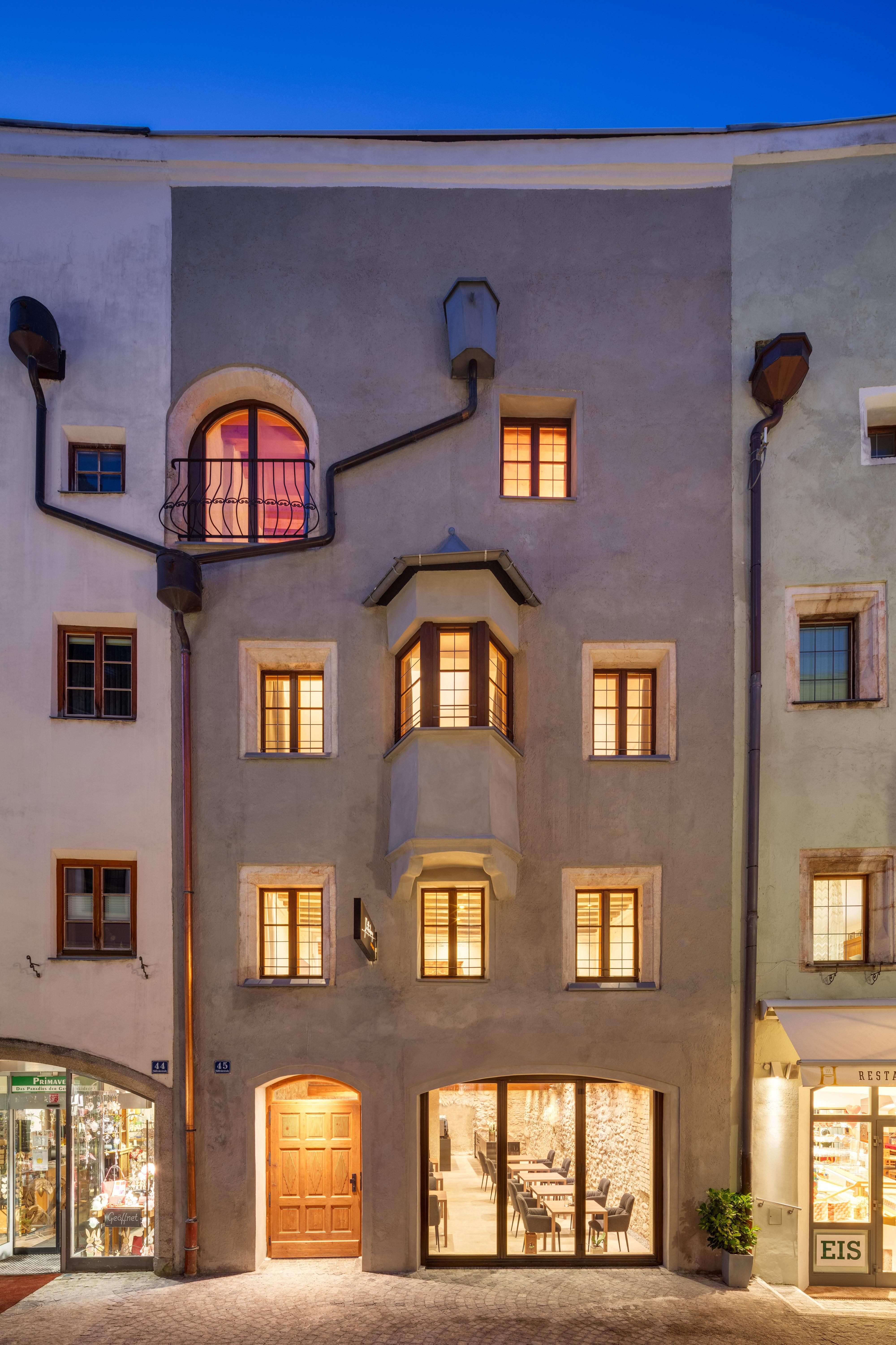 A historic building with a unique design and large windows. It is brightly lit and displays an inviting atmosphere.